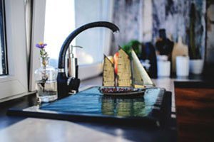 حنفية ماء على دلو يحوي ماء و فيه قارب مركب بالفوتوشوب