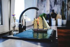 حنفية ماء على دلو يحوي ماء و فيه قارب مركب بالفوتوشوب